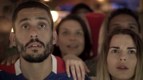 Football fans cheering while watching televised match in bar