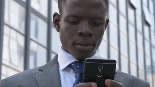 Busy black american business man typing on his smartphone in the street-close up