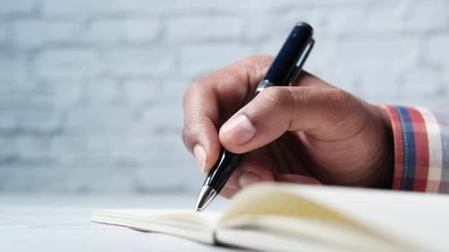 Close Up of Man Hand Writing on Notepad.