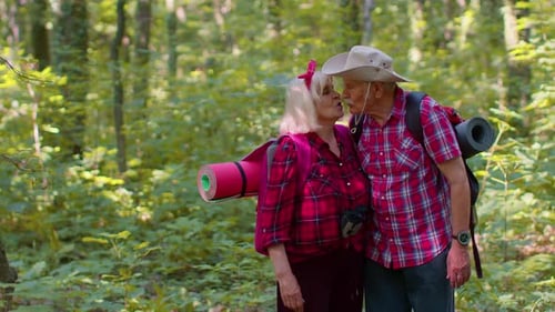 Happy Senior Couple Hiking Through the Green Forest
