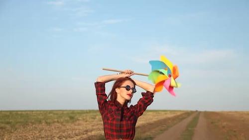Woman Smiling and Holding a Pinwheel in Field