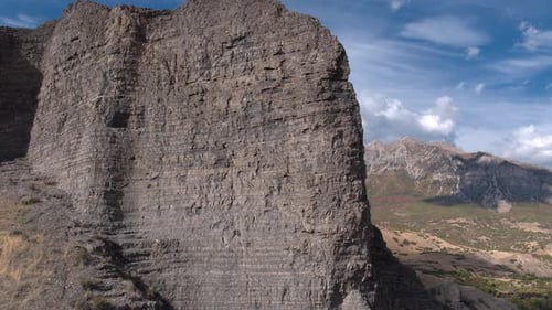 Aerial pan of rocky cliff revealing mountain