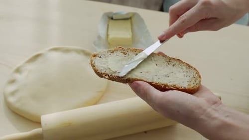 Hands Spreading Butter on a Slice of Bread