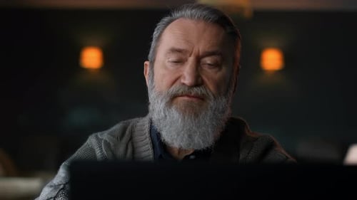Senior Man with Gray Beard Looking at Laptop