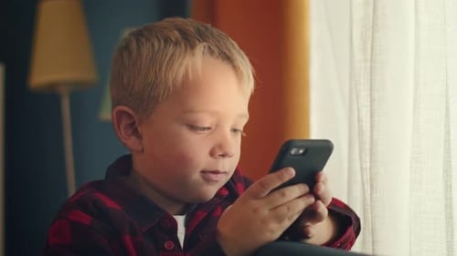 Child Uses a Smartphone Indoors During the Day