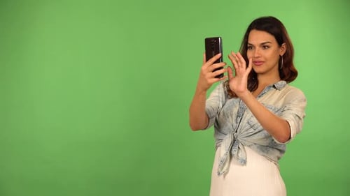 A Young Beautiful Caucasian Woman Takes Pictures with a Smartphone Green Screen Background