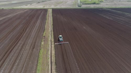 Traktor auf landwirtschaftlichen Flächen wird mit Düngemitteln kultiviert
