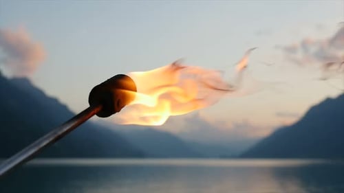 Burning Torch Flame at Mountain Lake Sunset