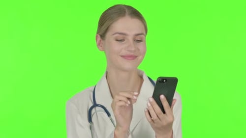 Female Doctor Browsing Smartphone on Green Background