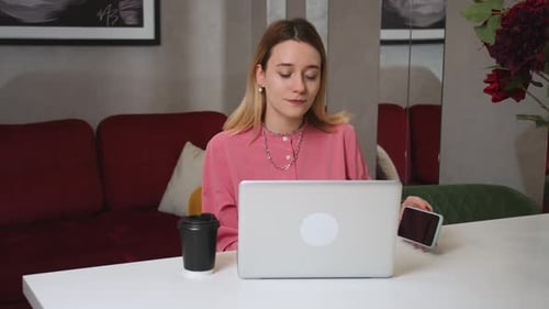 Mujer muy joven trabajando en una computadora portátil en casa hablando por teléfono y tenía malas noticias