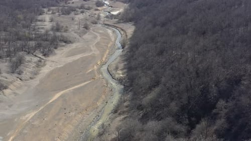 Mining drainage waste on polluted river coast 4K aerial video