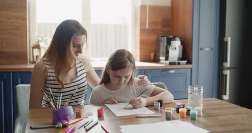 Mother and Daughter Painting Together at Kitchen Table