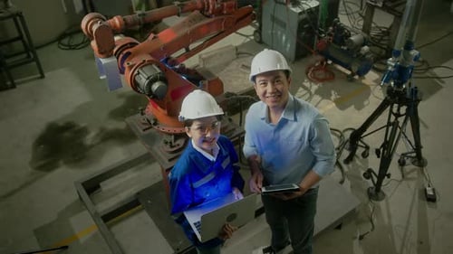 Engineers Working With Robotic Arm in Factory