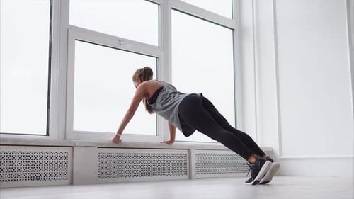 Beautiful Slim Brunette is Doing Some Pushups at the Gym