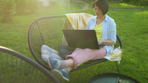 Freiberufliche Frau arbeitet zu Hause im Hinterhof am Laptop