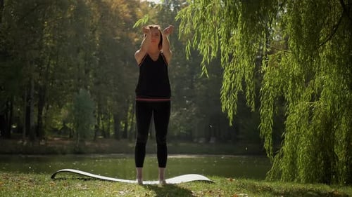 The Girl Performs Warmup Exercises Before Yoga in Nature n Park