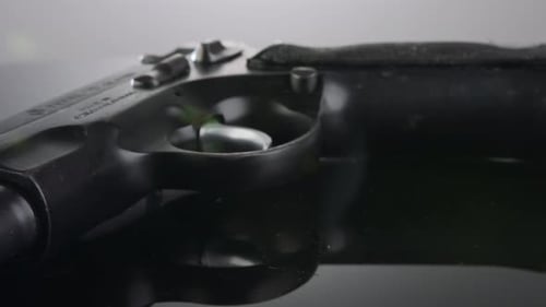 Waffenkontrolle. Studioaufnahme einer 9-mm-Pistole, die sich auf einer reflektierenden Oberfläche dreht