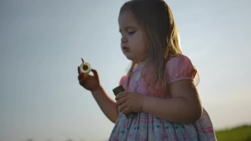 Side View of Little Girl in Blows Soap Bubbles on the Nature