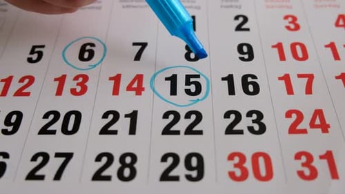 Dates Being Circled on a Calendar with Blue Pen