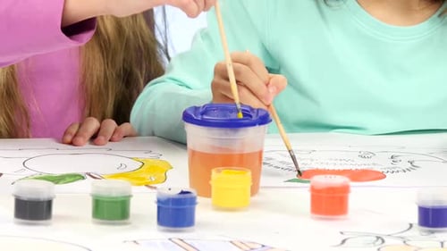 Small Children with the Help of Brushes and Paints Decorate Drawings, They Like It. Close Up. White