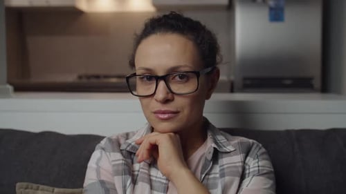 Woman with Glasses Posing Thoughtfully on Couch Indoors
