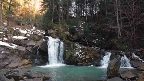 Mountain Waterfall with Turquoise Water Among the Snowy Stones and Forest, Carpathians in Winter.