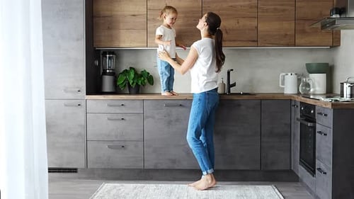 Loving Mother Holding Daughter in Modern Kitchen