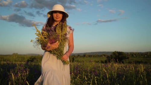 Young Woman Walking With Bouquet of Field Flowers
