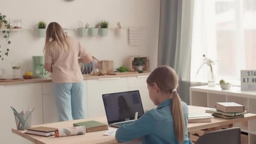 Girl Learning Online While Mother Works in Kitchen