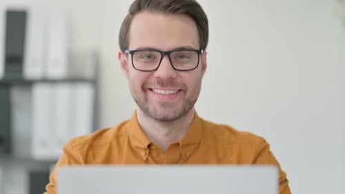 Close Up of Young Man with Laptop Smiling at the Camera