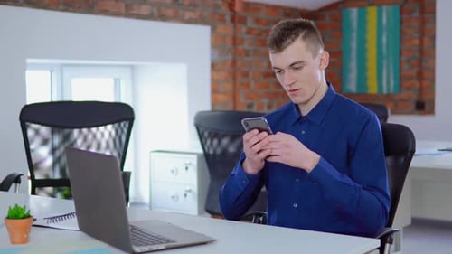Young Adult Using Phone at Desk in Office