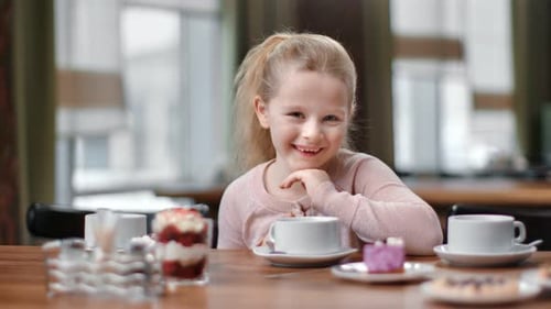 Portrait of Female Baby Posing at Cafe Table with Tea and Delicious