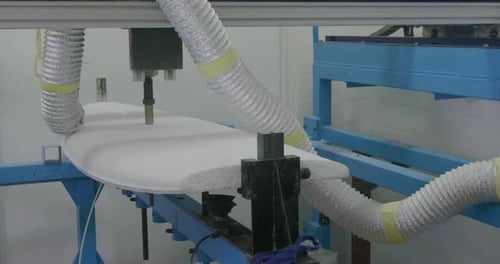 Surfboard being shaped by a machine in a workshop