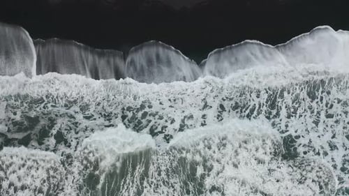 Drone shot of waves on black sand beach in Iceland.