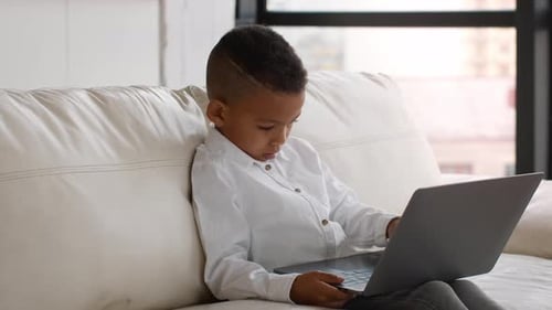 Young Boy Using Laptop Computer on Sofa