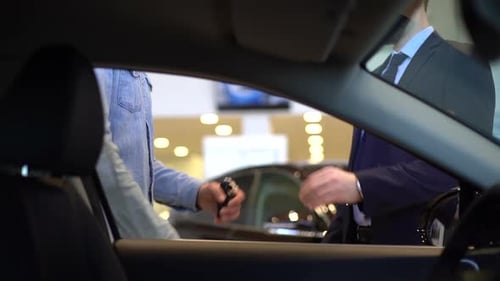 Close-up of Salesman Giving Car Keys To Customer and Shaking His Hand.