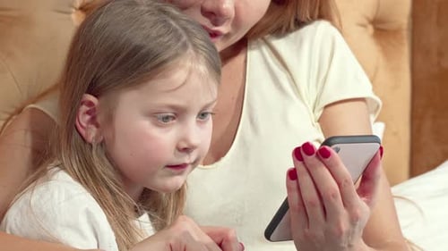 Child and Woman Looking at a Smartphone