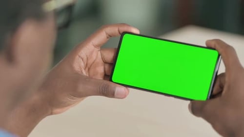 Close Up of Young African Man Watching Smartphone with Chroma Screen