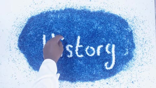 Hand Writes History in Blue Shavings