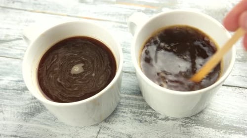 Two Mugs of Coffee, One Being Stirred