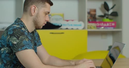 Young Adult Typing on Laptop Indoors