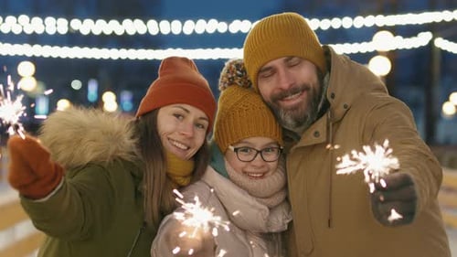 Happy Family Holding Sparklers on a Cold Night