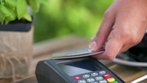 Hand Swiping Credit Card at Payment Terminal