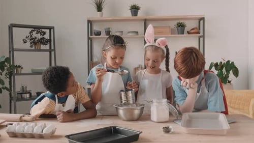 Vielfältige Kinder sieben Mehl in der Küche