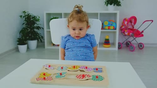 Adorable Girl Reaches for Wooden Puzzle at Table