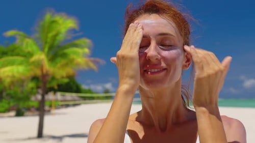 A Woman Passes Sunscreen on Face on a Sunny Day