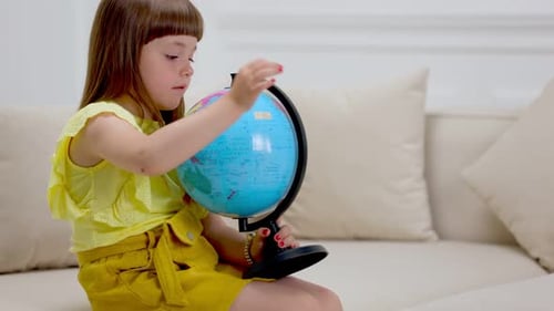 Little Girl Learning Geography with Globe at Home