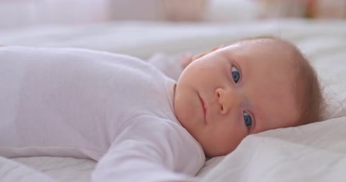 Cute Infant Lying Awake on White Blanket