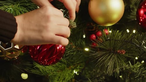 Close Up of Female Decorating Christmas Tree with Baubles