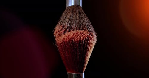 Zwei Make-up-Pinsel mit Puder auf schwarzem Hintergrund mit Sonnenlicht Colour Paint Concept Zeitlupe
